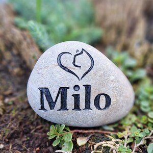 Op de afbeelding: Een grijs stenen hart gegraveerd met een pootprint en de naam "Milo".