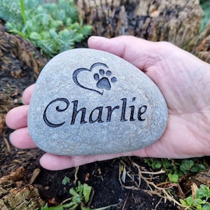 Op de afbeelding: Een grijze steen gegraveerd met een pootprint in een hart en de naam "Charlie".