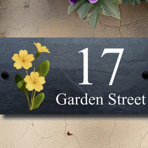 May include: Black slate house number sign with white painted number 17 and the text "Garden Street" and a yellow primrose flower design.