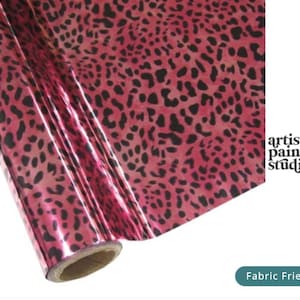 May include: A roll of metallic pink foil featuring a black leopard print pattern. The text artistic painting studio is visible on the right side, along with a teal rectangular label containing the white text Fabric Friendly.