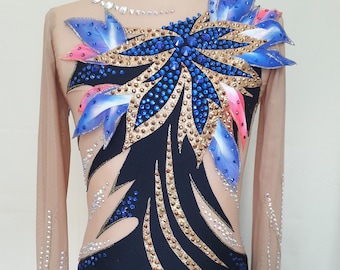 May include: A black and nude leotard with long sleeves and a large blue, gold, and pink flower design on the back. The leotard is covered in rhinestones.