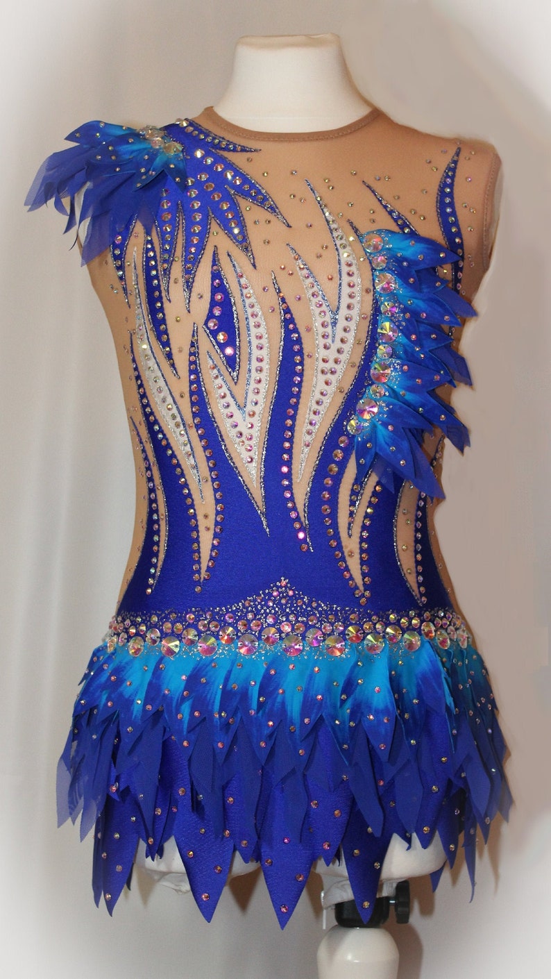 May include: A blue and white leotard with a feathered skirt. The leotard is decorated with rhinestones and has a blue and white flame design. The skirt is made of blue feathers and has a blue and white ombre effect.