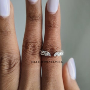 May include: A silver ring with a delicate design of marquise-shaped clear stones set in a leaf pattern. The ring is open on one side, making it an adjustable fit.