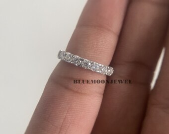 May include: A silver ring with a row of round, clear gemstones. The ring is set on a finger, with the brand name "BLUEMOONJEWEL" visible in the background.