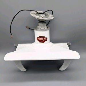 May include: A vintage white ceiling fan with a central motor housing and two curved blades. The fan has a silver-colored mounting plate and exposed wiring. The word "MULTI" is displayed on the motor housing in a red and gold emblem.