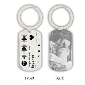 Op de afbeelding: Een zilveren sleutelhanger met een zwart-witfoto van een stel op de achterkant en een Spotify-barcode met het nummer "Dangerously in Love" van Beyoncé op de voorkant.