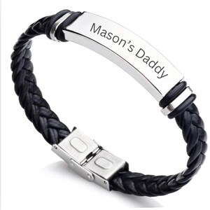 Könnte beinhalten: Schwarzes Lederarmband mit einer silbernen Platte, die mit dem Text "Mason's Daddy" graviert ist.