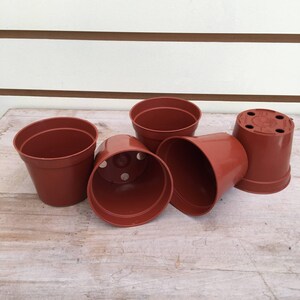 May include: Five brown plastic plant pots of various sizes. The pots have drainage holes in the bottom.