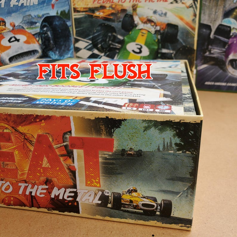 May include: A board game box with the text "FITS FLUSH" in red. The box features the title "HEAT: Pedal to the Metal" with images of race cars. Other game boxes are visible in the background, with images of race cars.