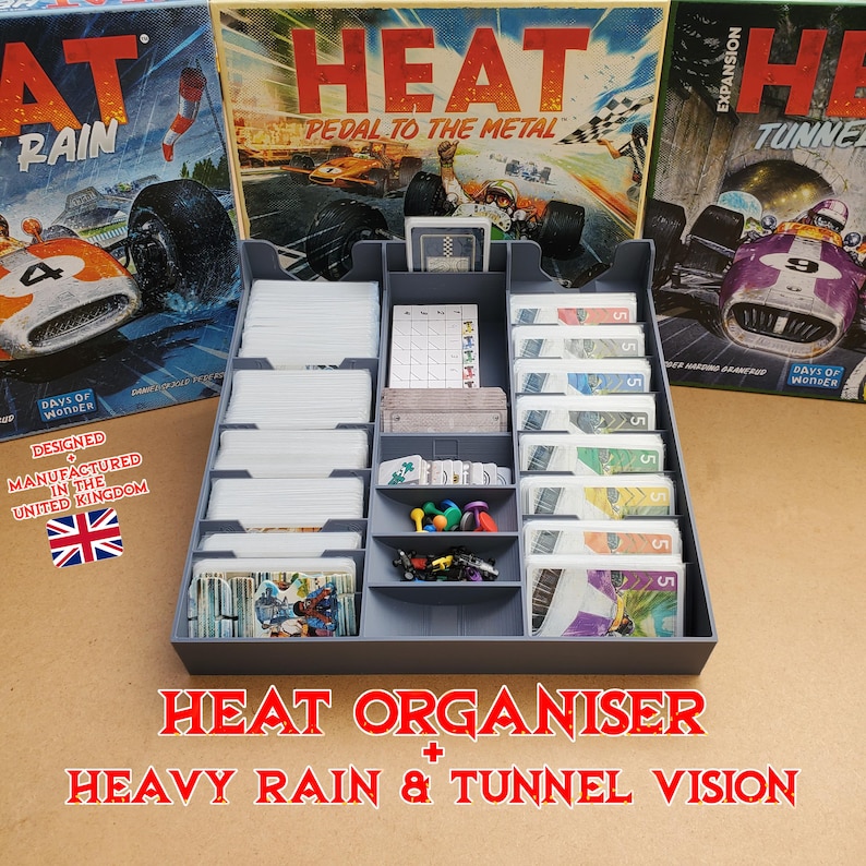 May include: A gray plastic organizer for the board game "Heat: Pedal to the Metal" and expansions. The organizer has multiple compartments for cards, tokens, and other game components. The game boxes are visible in the background.