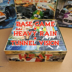 May include: A boxed board game set with the text "BASE GAME + HEAVY RAIN + TUNNEL VISION" in red. The box features vintage racing car illustrations and the words "PEDAL TO THE METAL" and "HEAT".