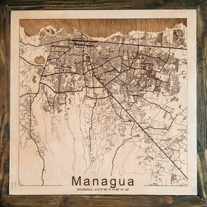 May include: A laser-engraved wooden map of Managua, Nicaragua. The map shows the city's streets and landmarks. The text "Managua" and "NICARAGUA N12&deg;07'58.15" W:86&deg;15'1.44" is printed below the map.