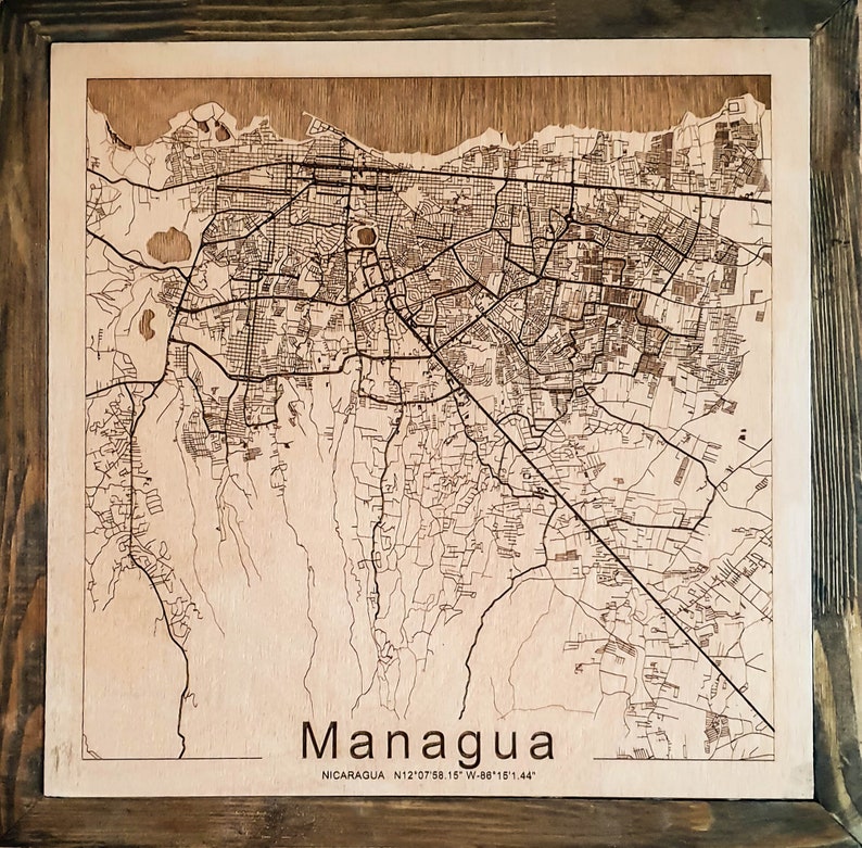 May include: A laser-engraved wooden map of Managua, Nicaragua. The map shows the city's streets and landmarks. The text "Managua" and "NICARAGUA N12&deg;07'58.15" W:86&deg;15'1.44" is printed below the map.