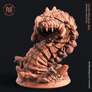 May include: A detailed, brown miniature of a monster with sharp teeth and claws. The creature has a segmented body and is posed on a cracked, circular base. The text "The Winter Hunt" is visible. The miniature is from "Flesh of Gods Miniatures."