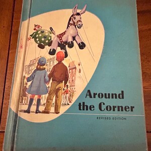 May include: A blue book with the title "Around the Corner" and the text "The Ginn Basic Readers" on the cover. The cover features an illustration of a blue donkey balloon floating above a street scene.