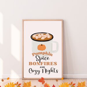 May include: A framed print featuring a white mug with a pumpkin graphic and a hot beverage topped with marshmallows. The text reads "Pumpkin Spice Bonfires and Cozy Nights" in a fall-themed design.