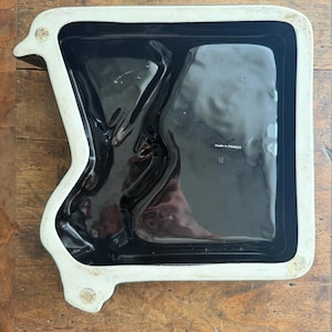 Pode incluir: Uma bandeja de cer&acirc;mica preta com borda branca. A bandeja tem uma forma irregular com um interior retangular. As palavras "made in France" e o n&uacute;mero "18" s&atilde;o vis&iacute;veis na bandeja.