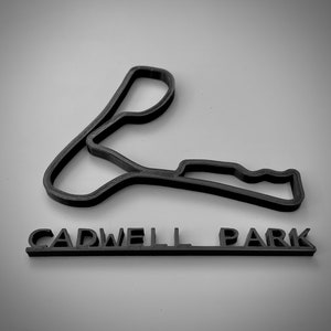 May include: Black 3D printed model of the Cadwell Park race track with the name "Cadwell Park" printed below.