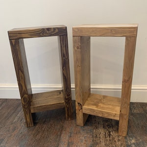 May include: Two wooden shelf units with a rustic finish. The shelf unit on the left is a darker brown colour, while the shelf unit on the right is a lighter brown colour.
