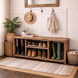 May include: Wooden shoe storage bench with a mirror and hooks. The bench is filled with shoes and boots. A woven rug and baskets are also present. A hat and bag hang on the wall. The room is decorated in neutral tones.