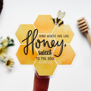 May include: A clear sticker with a honeycomb design and a bee illustration. The sticker features the text "Kind words are like honey, sweet to the soul. Proverbs 16:24".