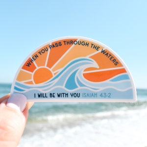 May include: A half-circle sticker with a sunset and wave design. The sticker has the text "WHEN YOU PASS THROUGH THE WATERS I WILL BE WITH YOU ISAIAH 43:2".
