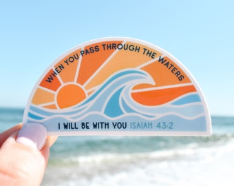 May include: A half-circle sticker with a sunset and wave design. The sticker has the text "WHEN YOU PASS THROUGH THE WATERS I WILL BE WITH YOU ISAIAH 43:2".