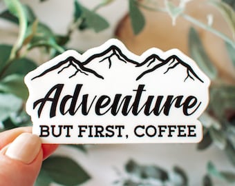 May include: White sticker with a black mountain range graphic and the text "Adventure but first, coffee".