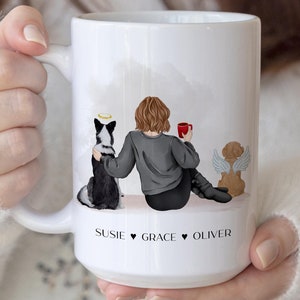 May include: White ceramic mug with a personalized illustration of a woman with two dogs. The woman is sitting with a cup of coffee and the dogs are sitting behind her. The mug has the names "Susie", "Grace", and "Oliver" written on it.