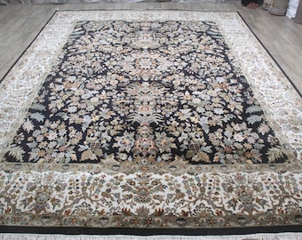 May include: A large, rectangular area rug with an intricate floral pattern. The rug features a black central field with a dense arrangement of beige, brown, and green floral motifs. A cream-colored border with similar floral designs surrounds the central field.