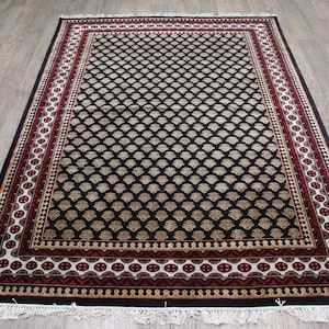 May include: Black and cream patterned rug with a red and white border. The rug has a traditional design with intricate details.