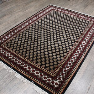 May include: Black and cream patterned rug with a red and gold border. The rug has a traditional design and is made of a soft, durable material.