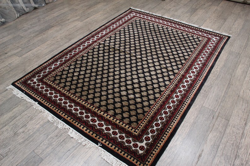 May include: Black and cream patterned rug with a red and gold border. The rug has a traditional design and is made of a soft, durable material.