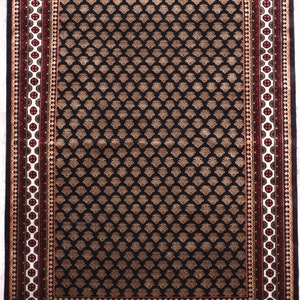 May include: Black rug with a geometric pattern in beige and white. The rug has a red and white border with a gold accent.