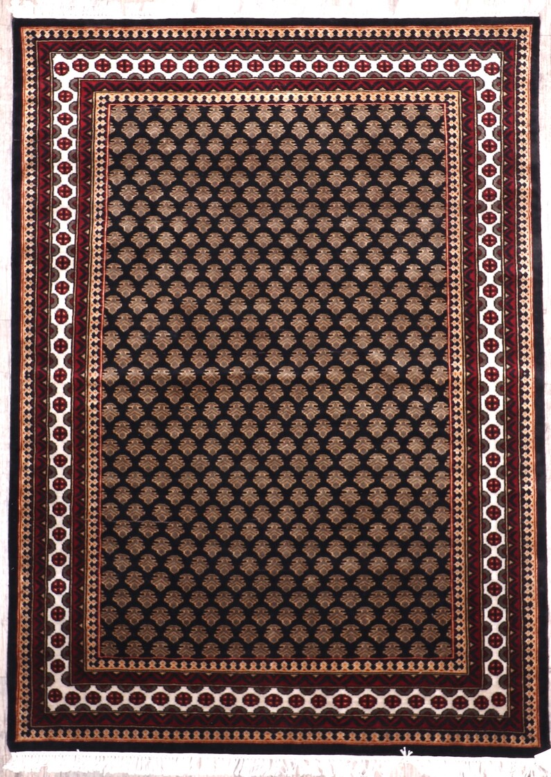 May include: Black rug with a geometric pattern in beige and white. The rug has a red and white border with a gold accent.