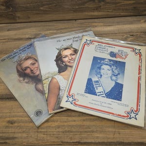 May include: Three vintage pageant programs. The covers feature portraits of women wearing crowns and sashes. The programs are from the 1977 and 1979 Miss Florida Pageants, and the Mrs. Florida America Pageant.