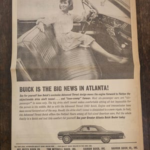 May include: A black and white newspaper advertisement for the 1962 Buick. The ad features a woman sitting in the driver's seat of a Buick. The headline reads "Buick is the Big News in Atlanta!" and highlights the car's Advanced Thrust design, which moves the engine forward to flatten the drive shaft tunnel. The ad also includes a list of local Buick dealerships.