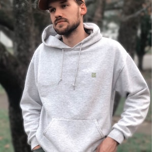 a man standing in front of a tree wearing a hat