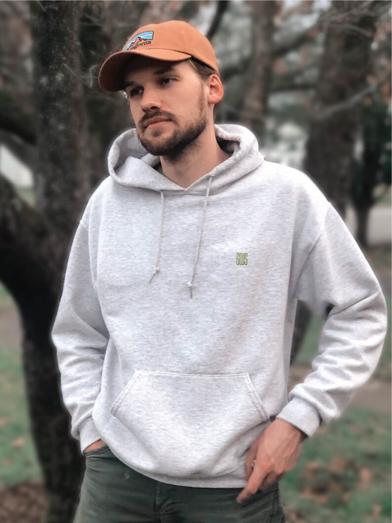 a man standing in front of a tree wearing a hat