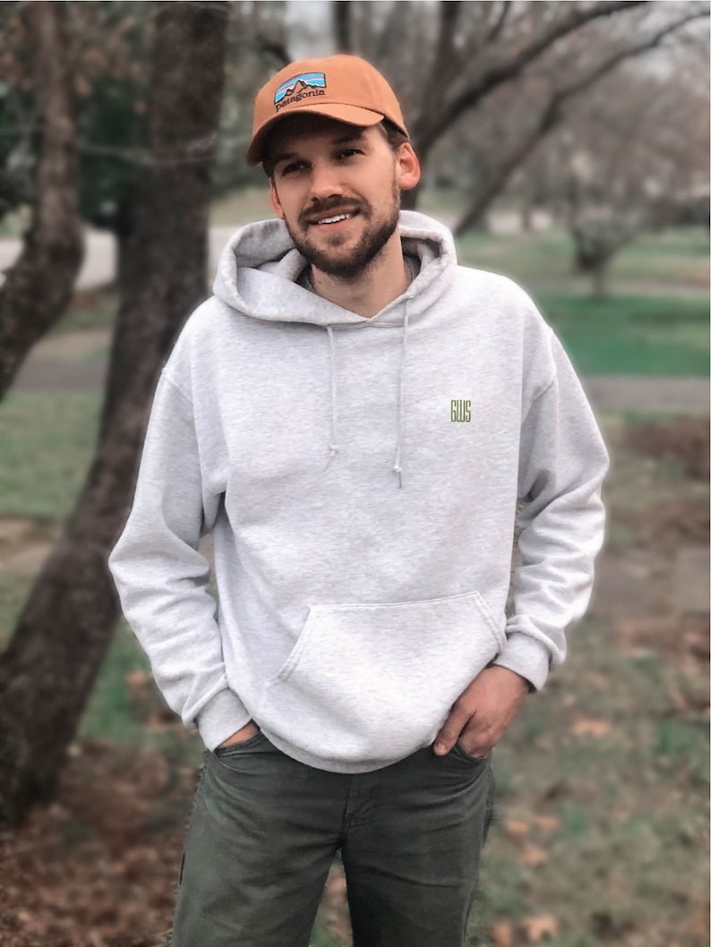 a man standing in front of a tree wearing a hat