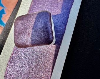 May include: A small sample of iridescent purple paint on a white paper background. The paint has a shimmery, glittery finish.