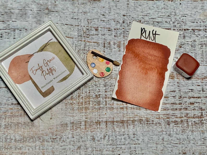 K&ouml;nnte beinhalten: Eine Aquarell-Farbpalette mit der Aufschrift "Rust" und einem braunen Aquarell-Farbmuster. Die Farbpalette befindet sich neben einem wei&szlig;en Rahmen mit dem Text "Emily Grace Patters Handmade Watercolors".