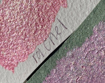Puede incluir: Primer plano de dos muestras de pintura de purpurina rosa y púrpura brillante. La muestra rosa está etiquetada como "ral 3011".