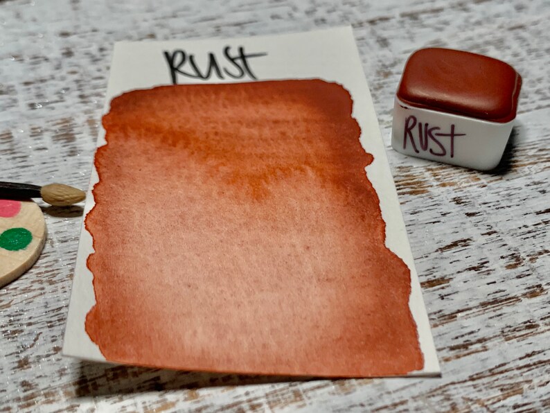 K&ouml;nnte beinhalten: Ein kleiner, quadratischer Beh&auml;lter mit Aquarellfarbe mit der Aufschrift "Rost". Die Farbe ist ein tiefes, r&ouml;tlich-braunes Braun.