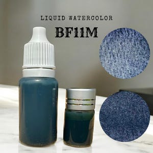 May include: Two bottles of blue liquid watercolor paint. The larger bottle has a white cap and the smaller bottle has a silver cap. The paint is labeled "BF11M" and "LIQUID WATERCOLOR".