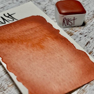 K&ouml;nnte beinhalten: Nahaufnahme einer Aquarell-Farbpalette mit der Aufschrift "Rust". Die Farbe ist ein tiefes Orangebraun.