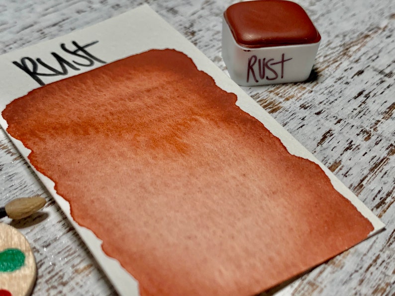 K&ouml;nnte beinhalten: Nahaufnahme einer Aquarell-Farbpalette mit der Aufschrift "Rust". Die Farbe ist ein tiefes Orangebraun.