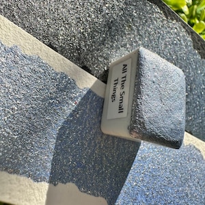 Peut inclure: Un petit récipient carré de peinture bleue pailletée avec le texte "All The Small Things" sur l'étiquette.