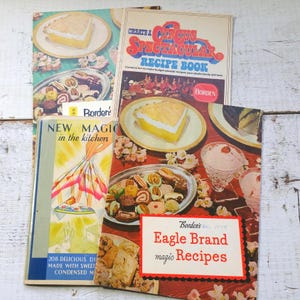 May include: A collection of vintage recipe books with colorful covers. Titles include "Create a Circus Spectacular Recipe Book" and "Eagle Brand magic Recipes." The covers feature illustrations of desserts and baked goods, with the Borden's logo.