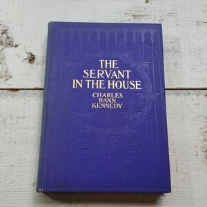 May include: A blue hardcover book with gold lettering titled "The Servant in the House" by Charles Rann Kennedy.